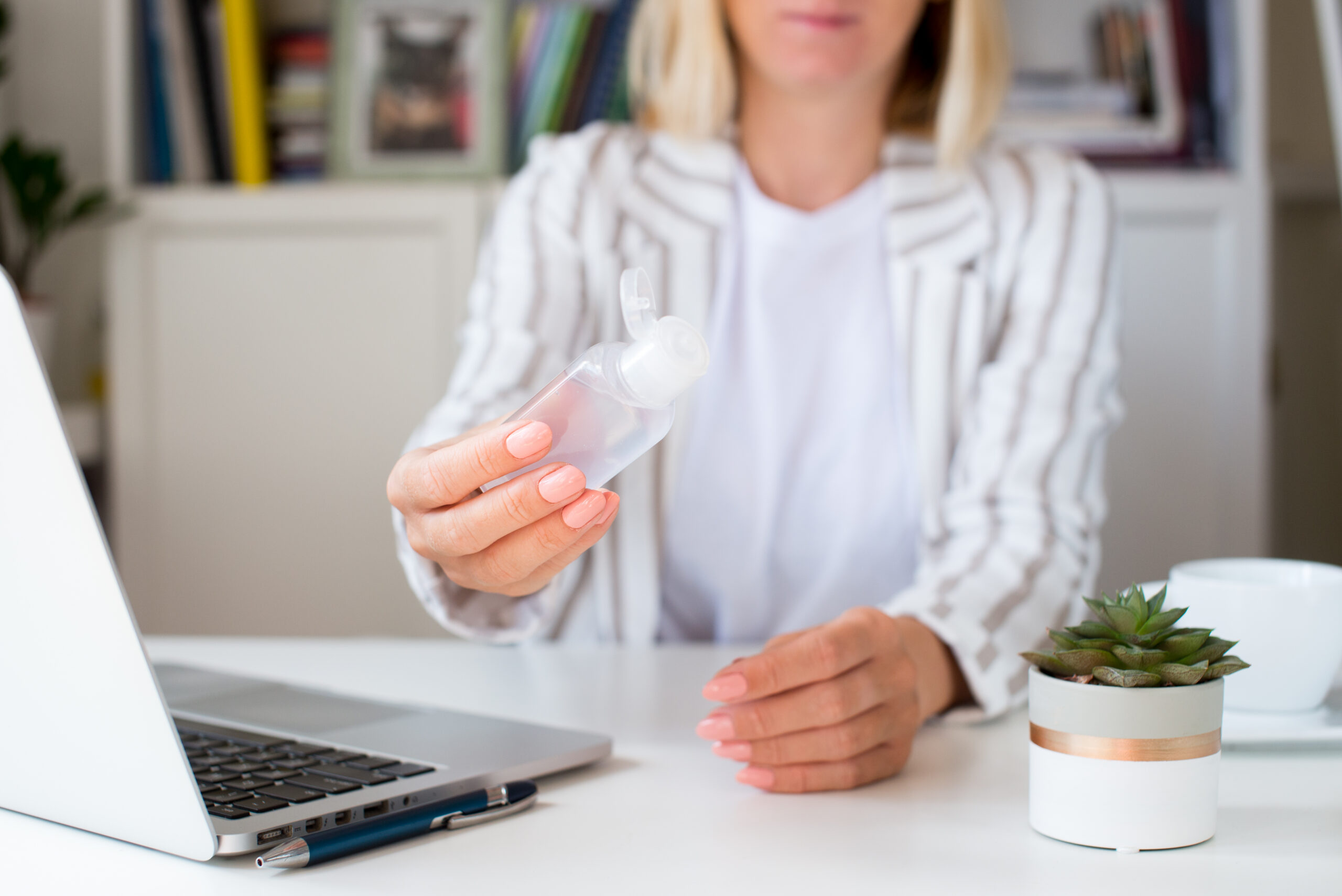 Businesswoman with hand sanitiser to help protect against Covid-19 Businesswoman at a desk with hand sanitiser to help protect against Covid-19